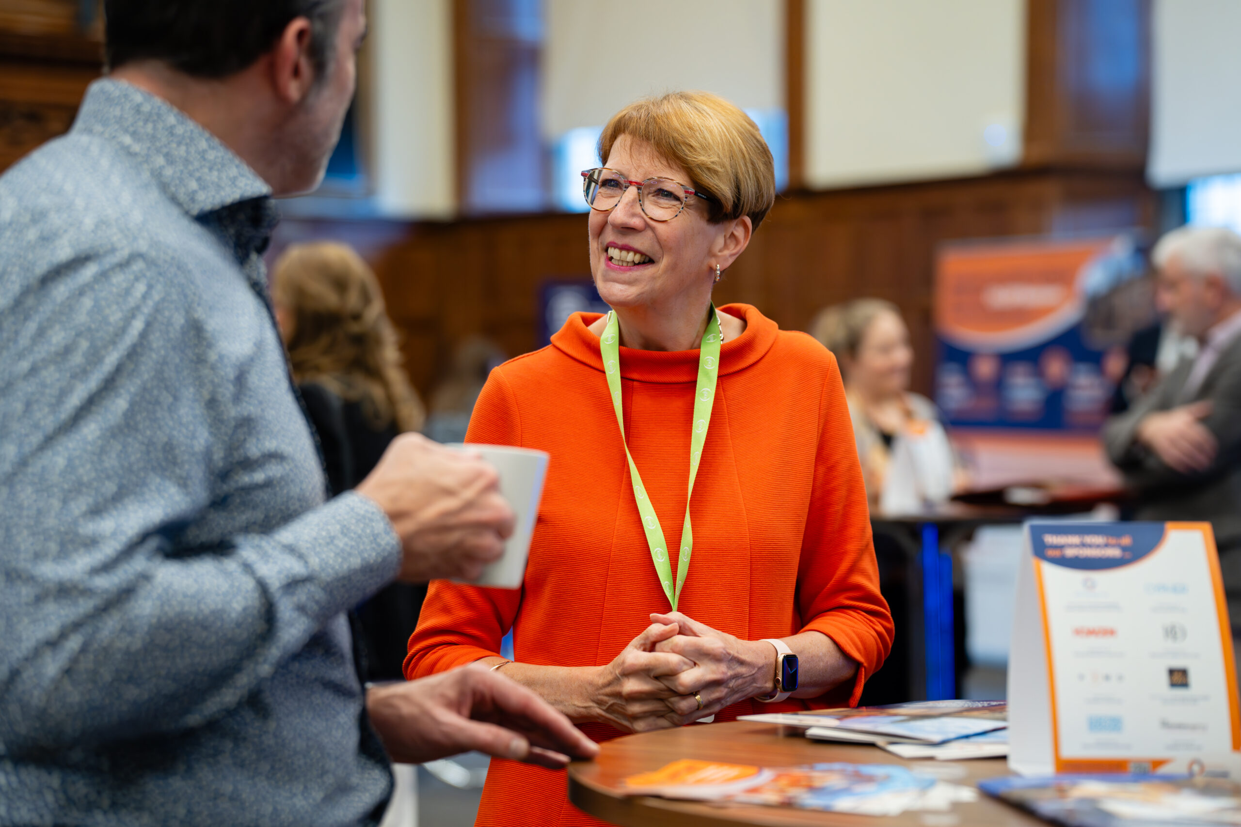 Image of individual smiling at business networking event whilst talking to another attendee